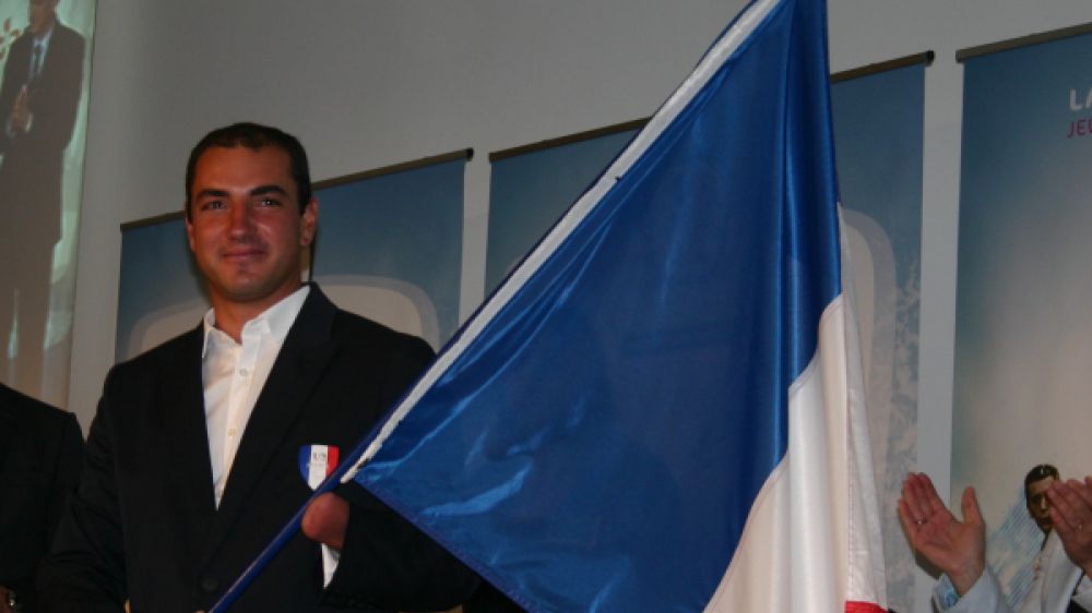 Damien Seguin avec le drapeau remis par Assia El Hannouni, porte-drapeau des Jeux de P&eacute;kin